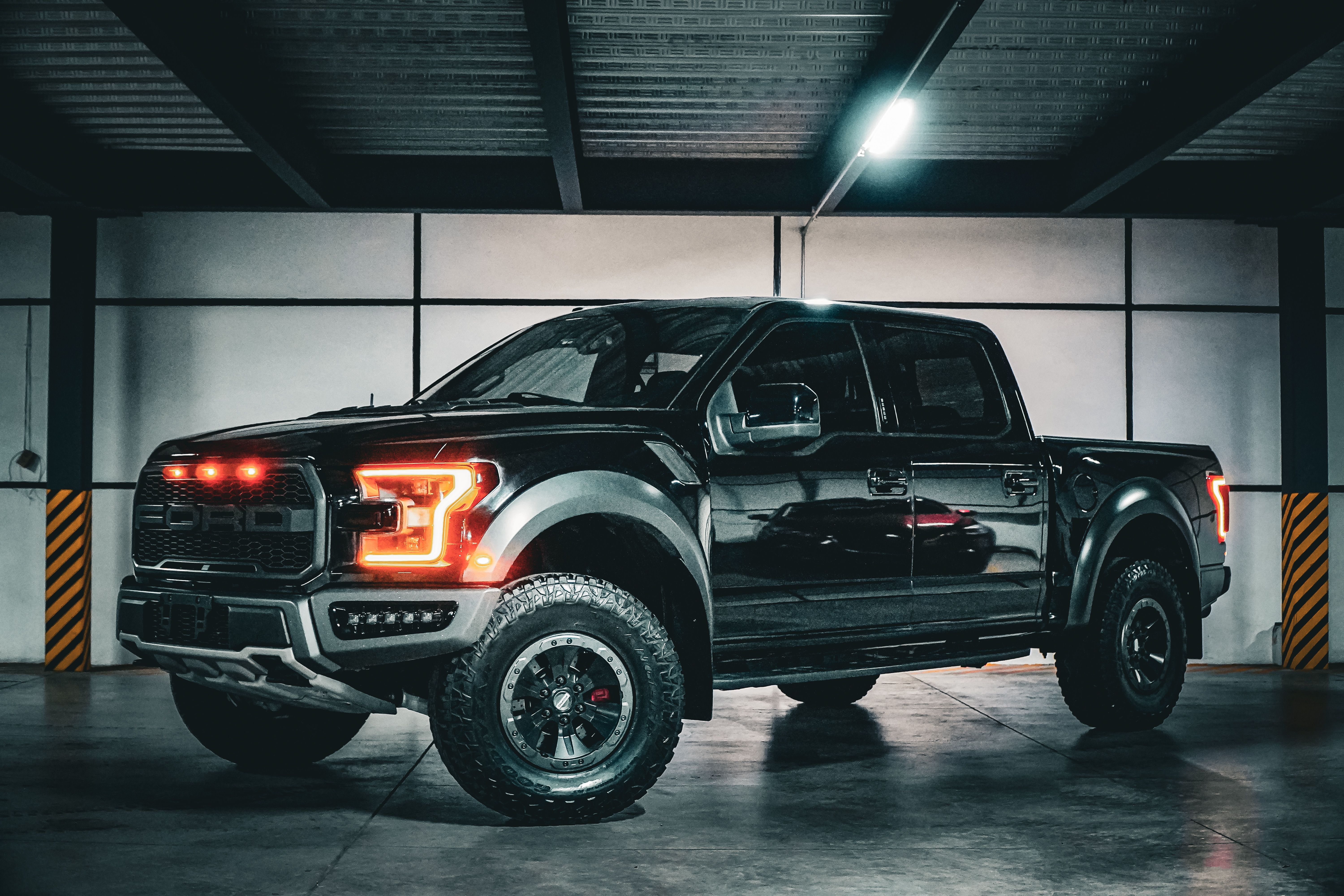 Black pickup truck with illuminated front lights in a garage