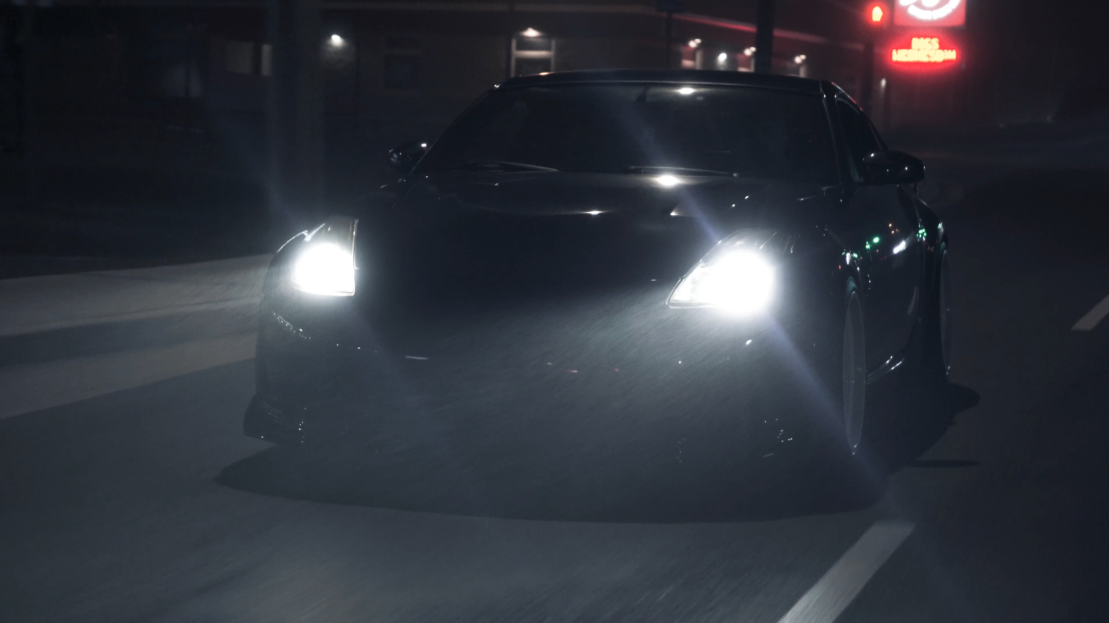 Dark performance car driving at night with bright headlights
