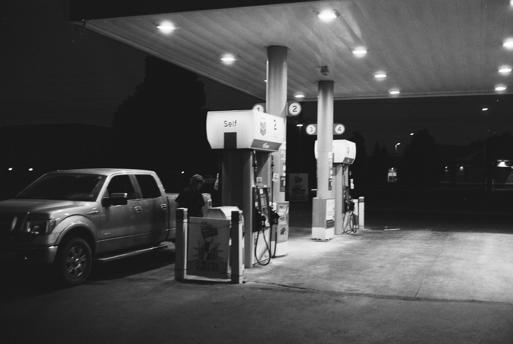 Pickup truck parked beneath gas station lights at night