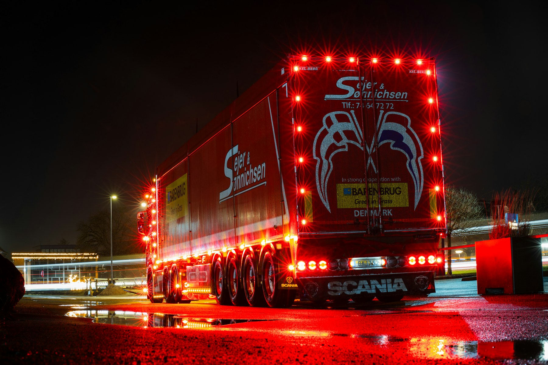 Red truck with tail lights illuminated in rainy night conditions