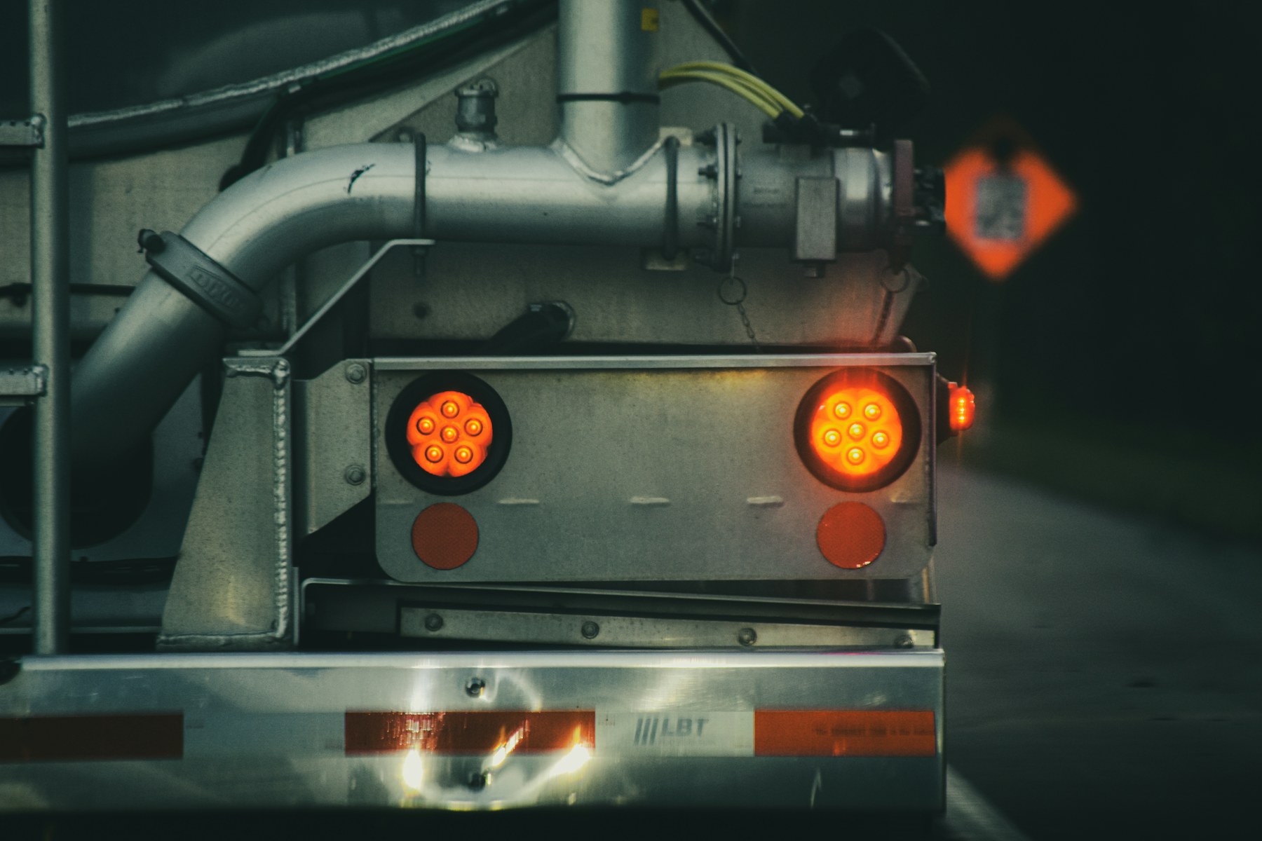 Truck rear lights glowing on a wet road at night